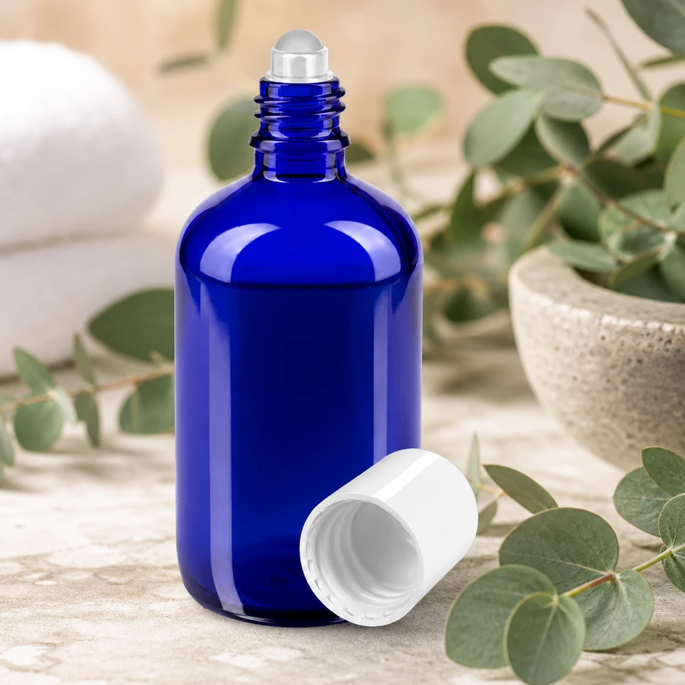 Apothekenflasche blau 100ml Roll-On Verschluss weiß Blaue Apothekerflasche 100ml mit Rollapplikator auf hellem Steinuntergrund neben Grünpflanzen