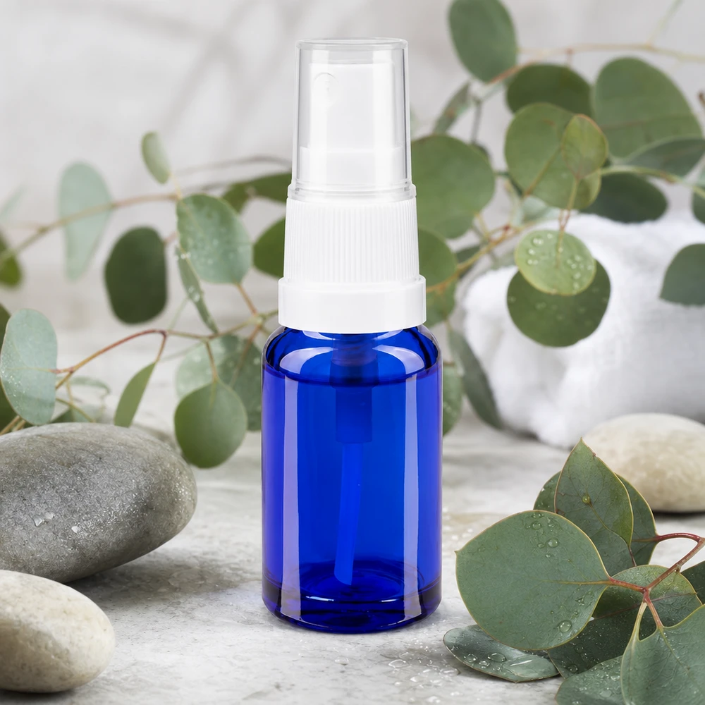 Apothekenflasche blau 10ml Sprayaufsatz weiß Kompakte blaue Glassprayflasche 10ml mit Standardpumpkopf auf Marmor neben Spa-Steinen