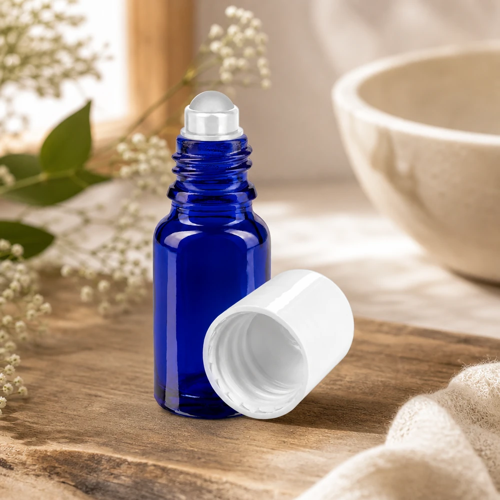 10ml blaues Apothekerglas mit Rollkugel-Applikator und weißer Kappe zwischen getrockneten Blüten