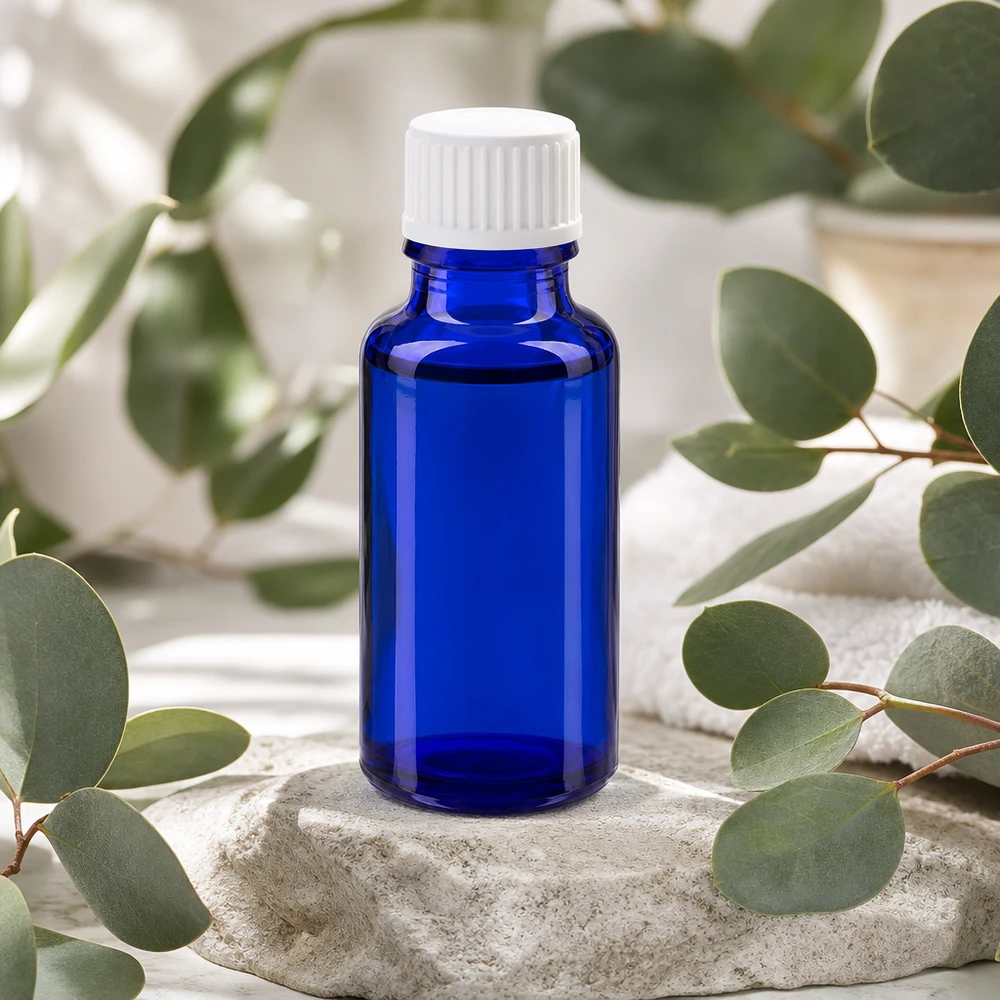Kobaltblaue 20ml Tropfflasche mit weißem Verschluss zwischen Eukalyptuszweigen