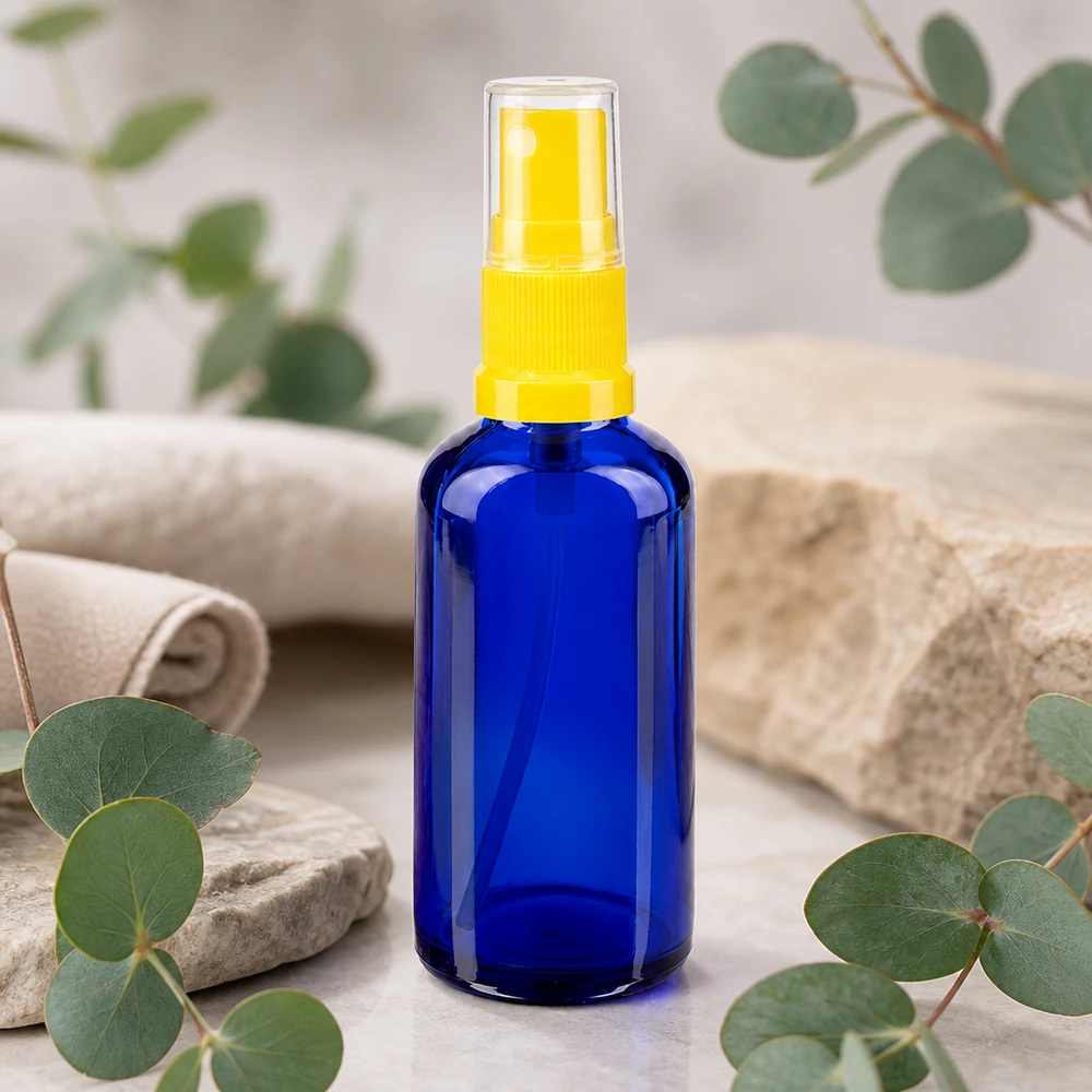 Apothekenflasche blau 50ml Sprayaufsatz gelb 50ml Blauglas-Flasche mit STD-Sprühkopf gelb zwischen Eukalyptuszweigen und Naturstein