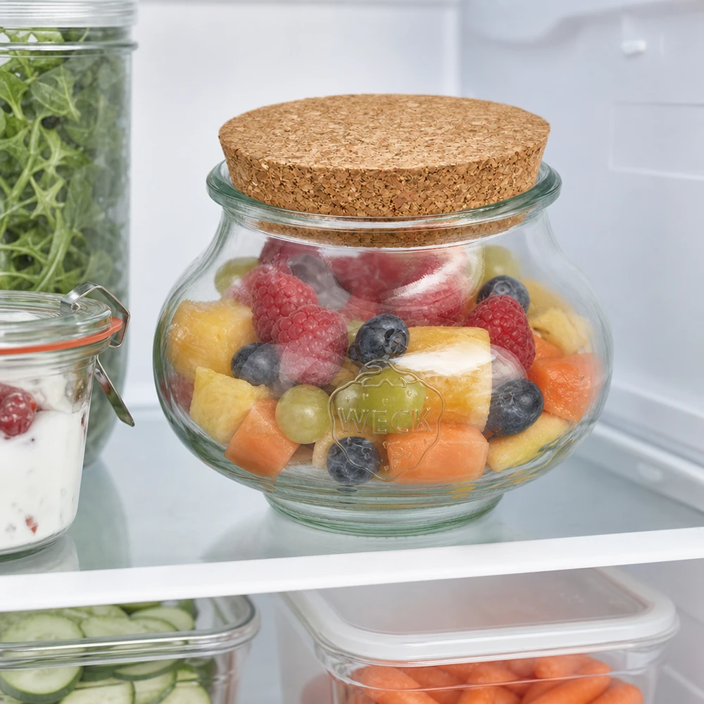 WECK Schmuckglas 560ml mit Korkdeckel im Kühlschrank gefüllt mit frischem Obstsalat neben anderen Vorratsgläsern