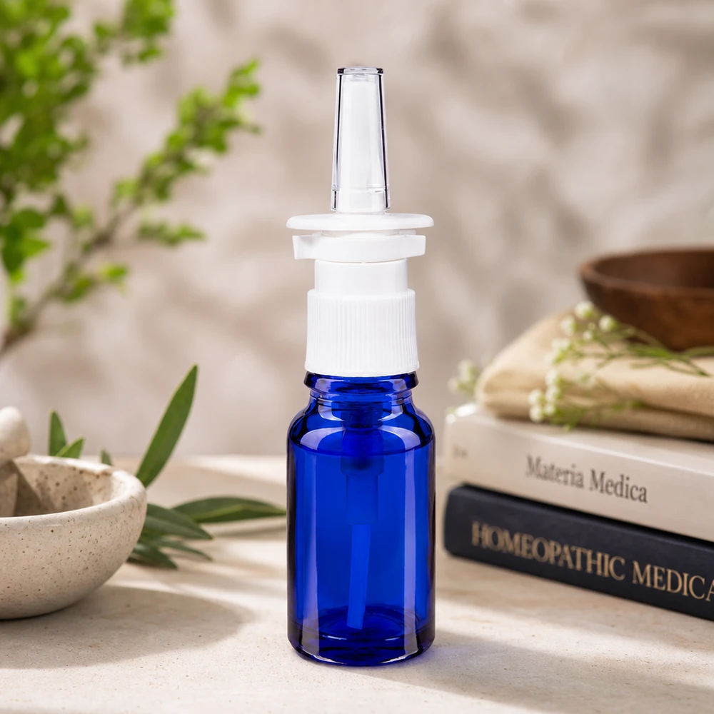 Apothekenglas 10ml in Blau mit Nasensprayaufsatz vor Materia Medica Homöopathie-Büchern