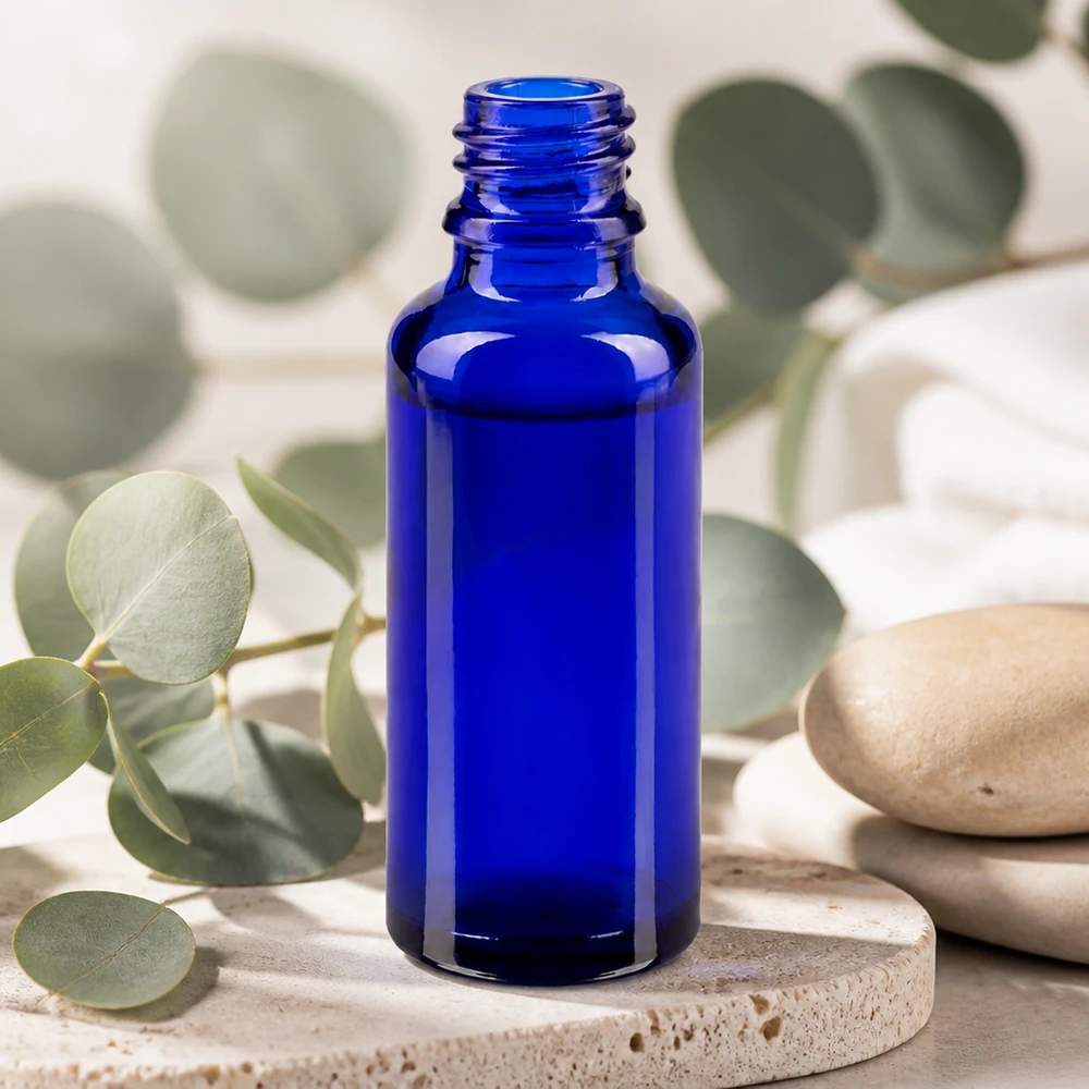 Kleine blaue Glasflasche ApoGlas 30ml auf Naturstein mit Eukalyptuszweigen im Wellness-Stil