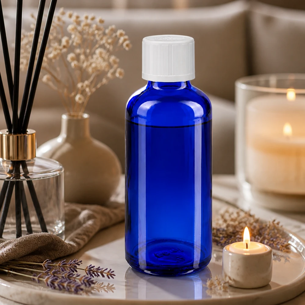 Blaue 50ml Glasflasche mit 1,2mm Tropfeinsatz neben Raumduft-Diffuser und Teelicht auf Marmortablett