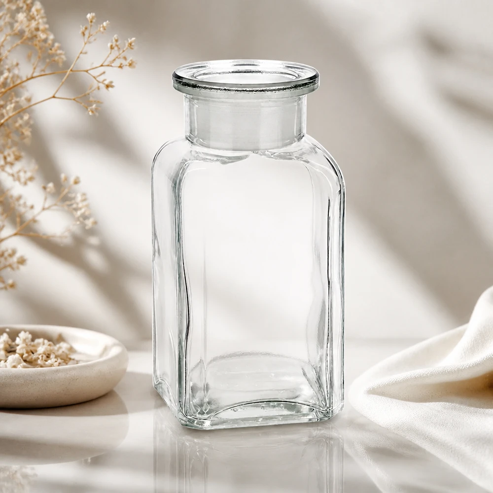 Kleine Apothekerflasche aus Klarglas 100ml viereckig mit Stopfen neben Keramikschale