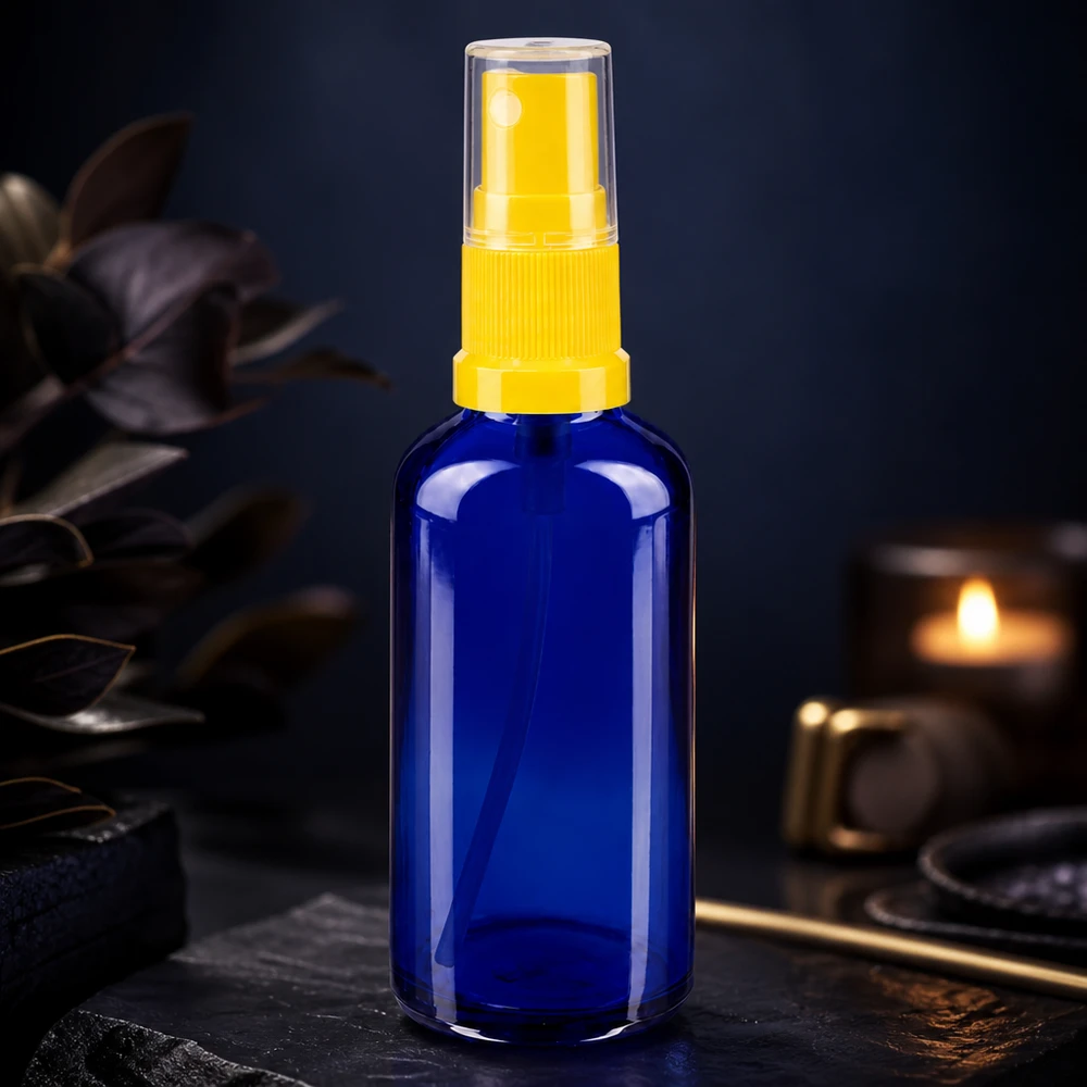 Apothekenflasche blau 50ml Sprayaufsatz gelb Blaue Glasflasche 50ml mit gelbem Sprühkopf neben Kerze und dunklen Blättern