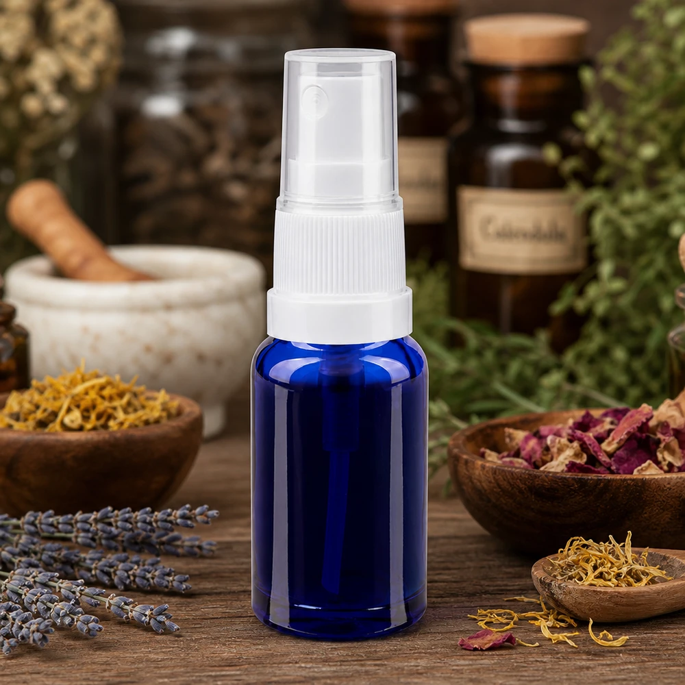 Kleine blaue Glasflasche mit Sprühkopf neben Mörser Trockenblumen und Apothekerflaschen im Hintergrund