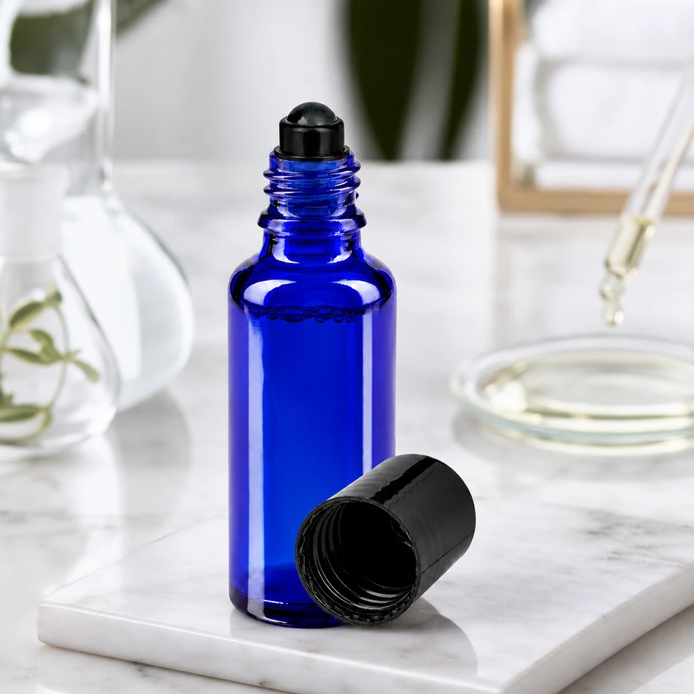30ml blaue Roll-On Flasche aus UV-Schutzglas mit schwarzer Rollkugel auf Marmor Untergrund