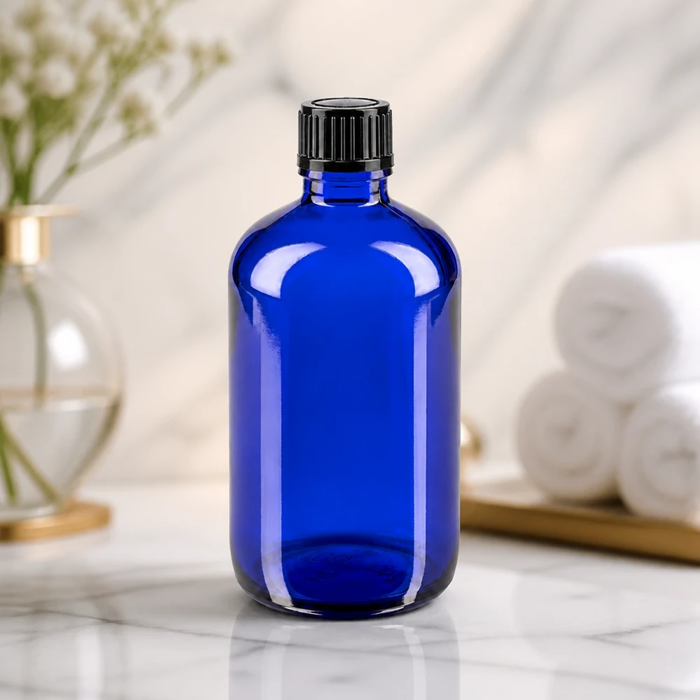 Apothekenflasche blau 100ml Schraubverschluss schwarz Standard Kobaltblaue Apothekerflasche 100ml neben weißen Handtüchern und goldenem Tablett im Spa-Ambiente