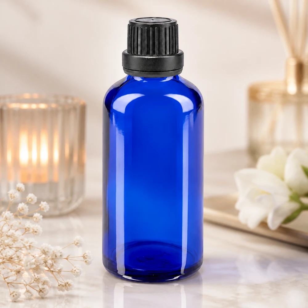 Apothekenflasche blau 50ml Tropfverschluss Giessring 2mm schwarz Originalitätsverschluss Blaue Apothekerglasflasche 50ml mit OV-Verschluss auf Marmoroberfläche in elegantem Wellness-Setting