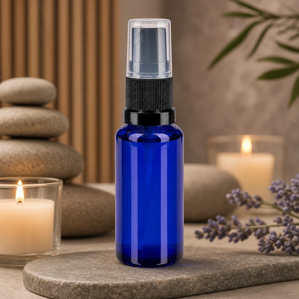 Apothekenflasche blau 30ml Sprayaufsatz schwarz Aromatherapie Zerstäuberflasche 30ml blau mit transparenter Kappe neben Lavendelblüten und Kerzen
