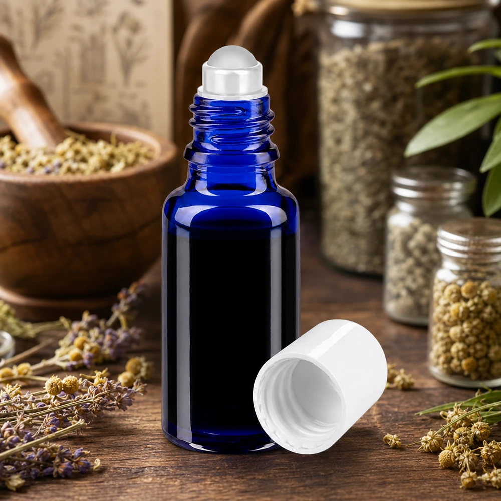 Kobaltblaue 20ml Roll-On Glasflasche geöffnet neben Kräutergläsern und getrockneten Blüten