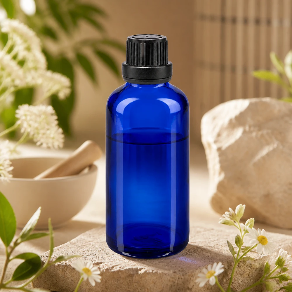 Apothekenflasche blau 50ml Tropfverschluss Giessring 2mm schwarz Originalitätsverschluss 50ml blaue Apothekerglasflasche mit OV-Verschluss und Tropfeinsatz umgeben von weißen Wildblumen