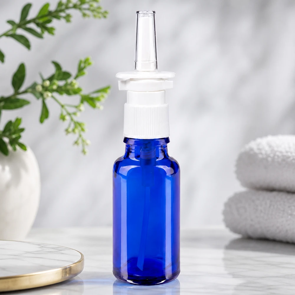 Kompakte Nasensprayflasche 20ml aus kobaltblauem Glas mit weißem Sprühaufsatz vor Naturkulisse