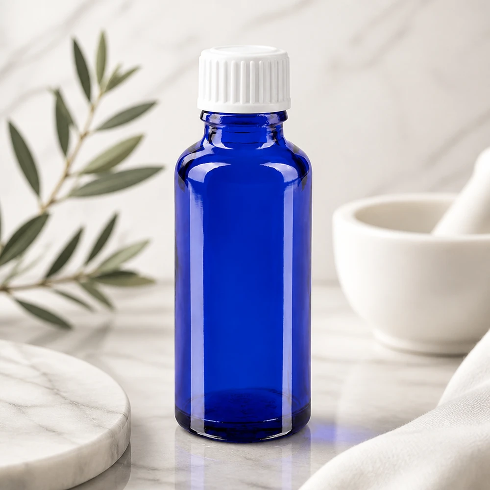 Apothekenflasche blau 30ml Schraubverschluss weiß Globuli Standard Blaue Glasflasche 30ml GR STD mit 3mm Tropfeinsatz auf Marmor neben Mörser und Pistill