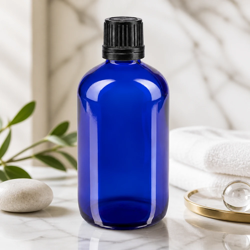 Apothekenflasche blau 100ml Schraubverschluss schwarz Giessring Originalitätsverschluss Blaue 100ml Glasflasche mit schwarzem OV-Verschluss auf Marmor neben weißem Handtuch