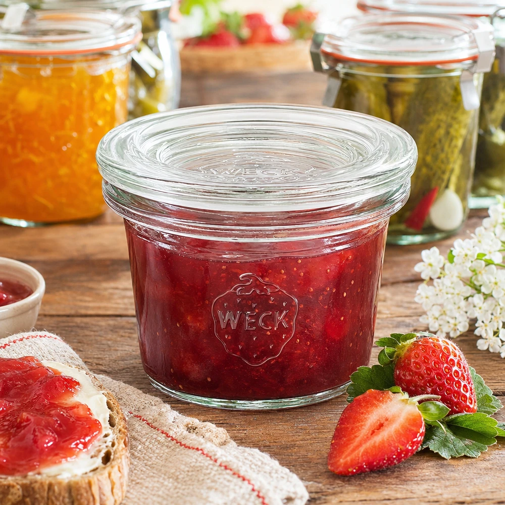 WECK Sturzglas 35ml RR40 mit roter Erdbeermarmelade gefüllt neben frischen Erdbeeren und Marmeladenbrot