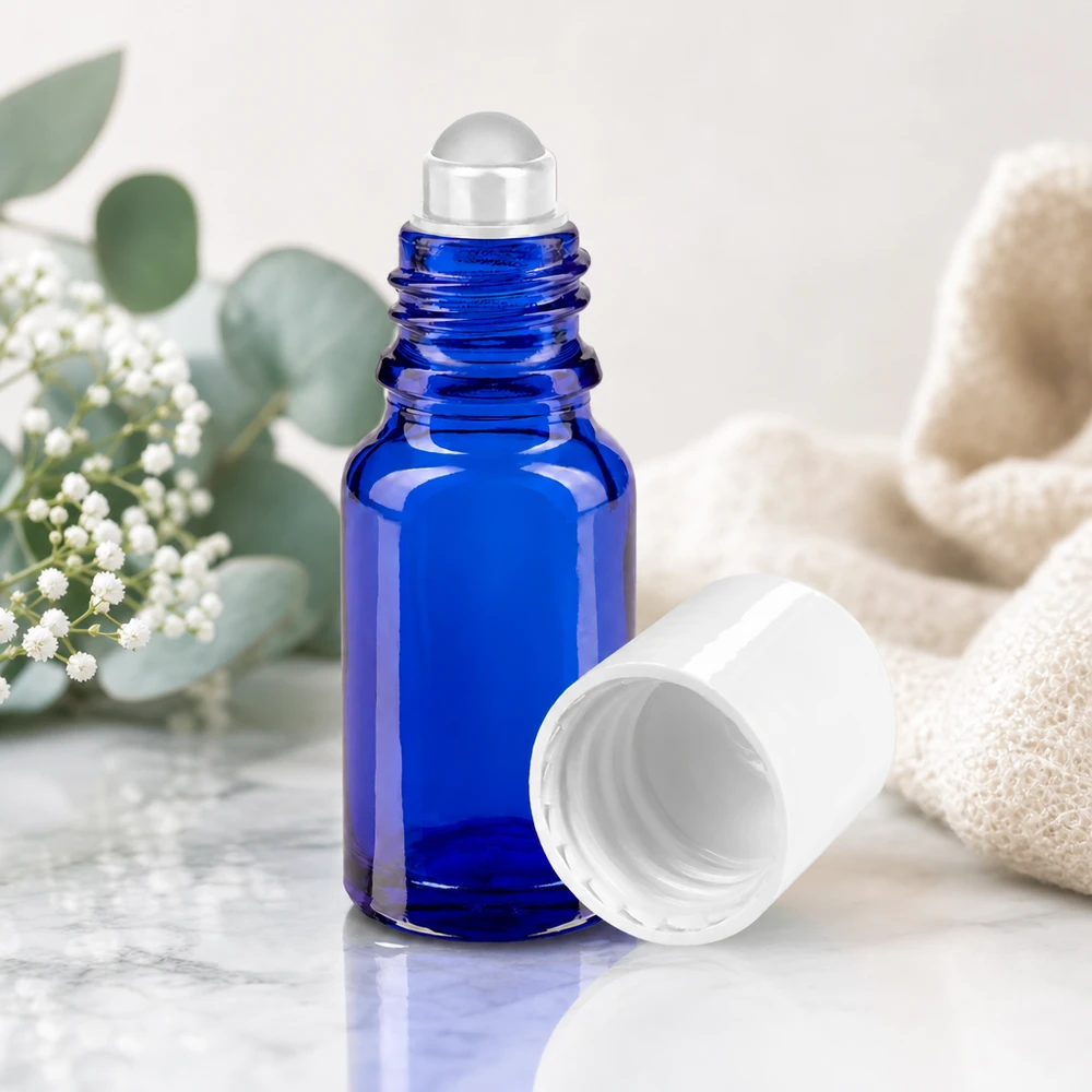 10ml Roll-On Flasche aus blauem Schutzglas mit weißer Kappe neben Eukalyptuszweigen