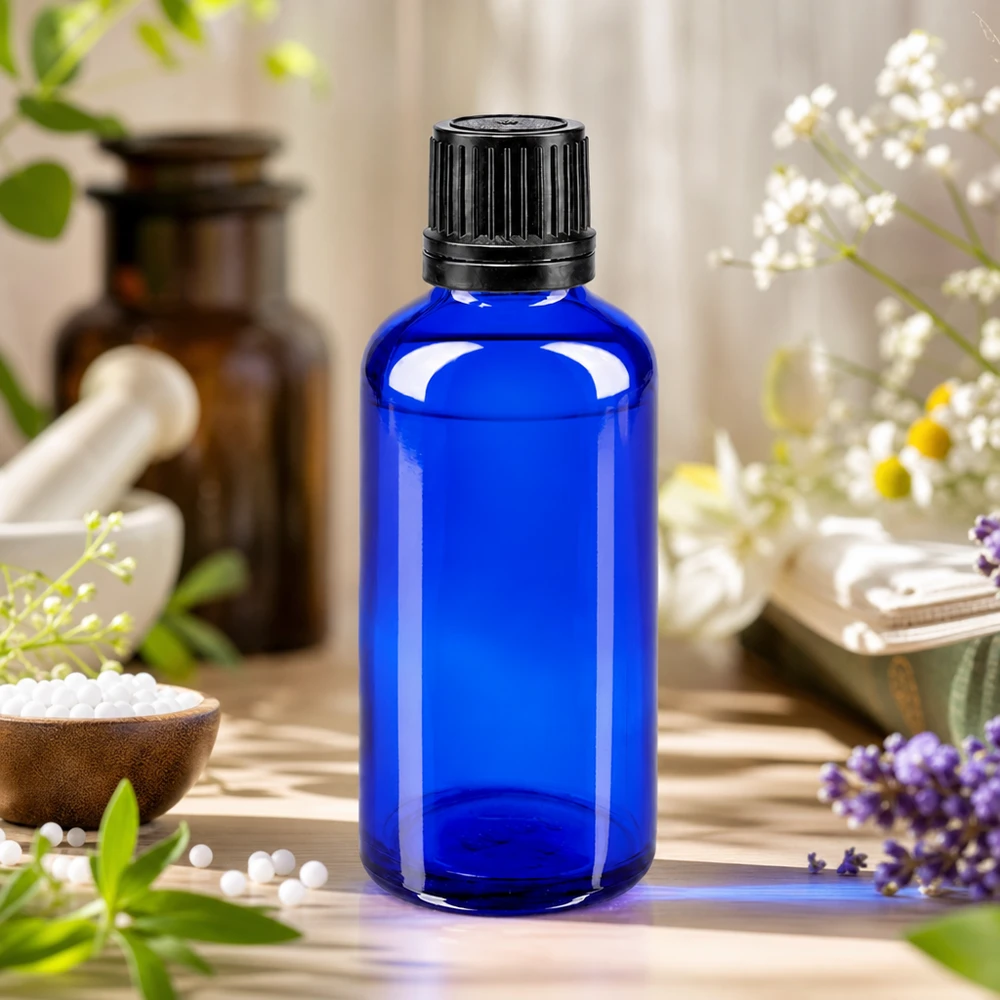 Apothekenflasche blau 50ml Schraubverschluss schwarz Giessring Originalitätsverschluss Kobaltblaue Glasflasche 50ml mit schwarzem OV 8mm neben Mörser und homöopathischen Globuli