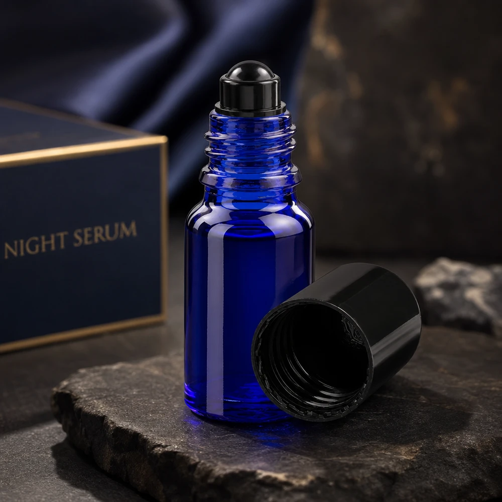 Apothekenflasche blau 10ml Roll-On Verschluss schwarz Kobaltblaue Roll-On Glasflasche 10ml mit schwarzer Kugel neben luxuriöser Night Serum Verpackung