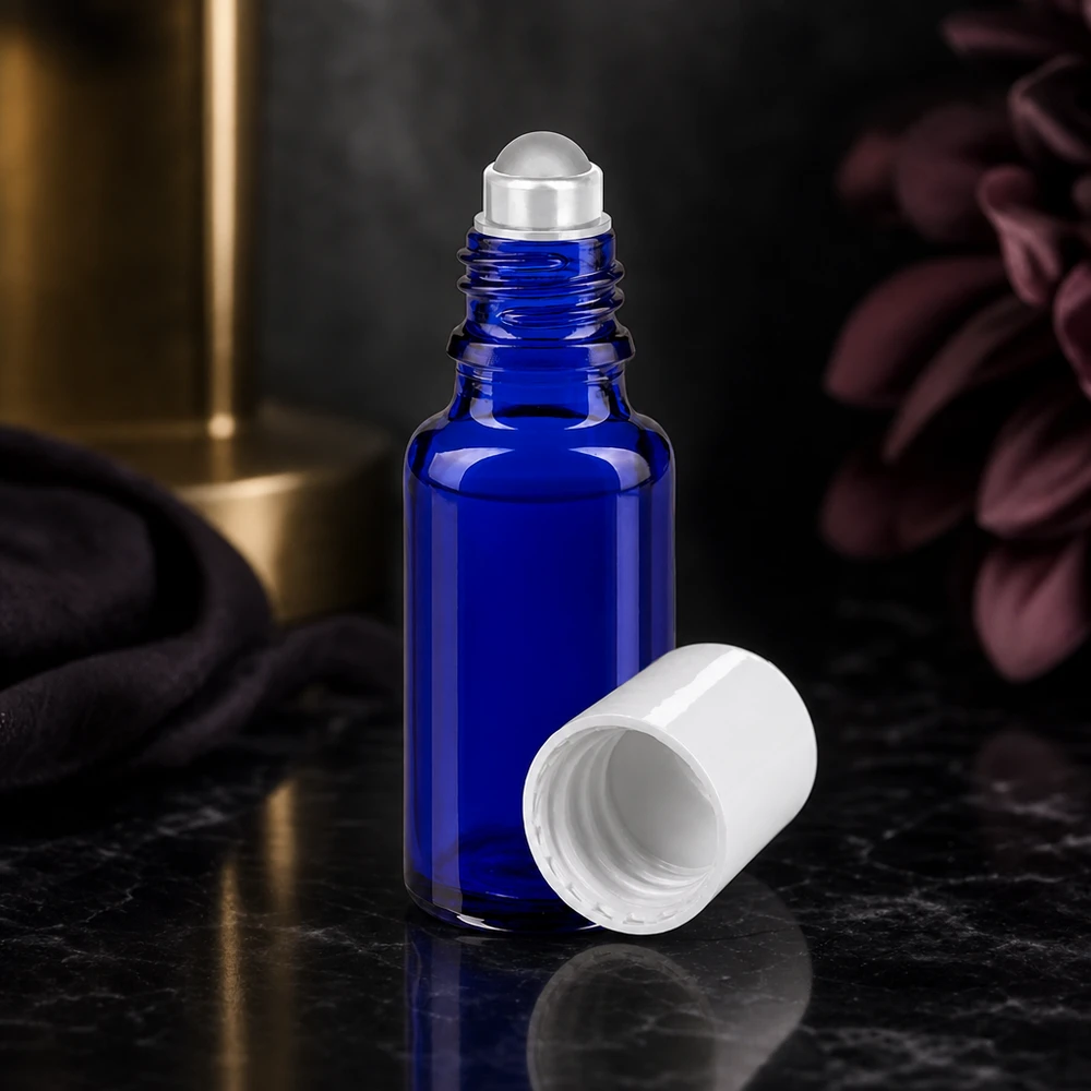 Kobaltblaue Glasflasche 20ml mit Edelstahl-Rollkugel und abgenommenem weißem Deckel auf Marmor