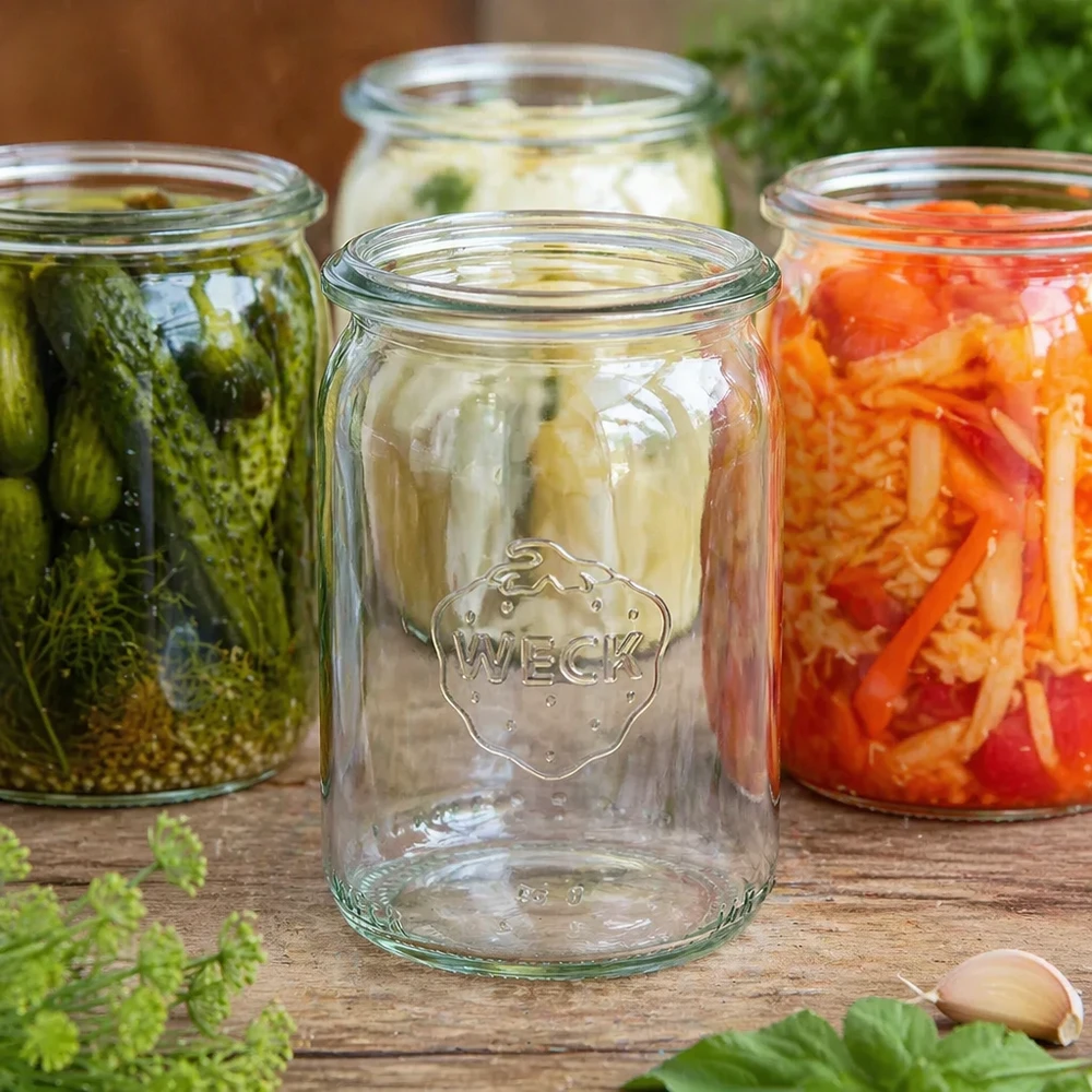 WECK Zylinderglas 145ml RR40 leer zwischen gefüllten Einmachgläsern mit eingelegtem Gemüse und Fermentation auf Holztisc